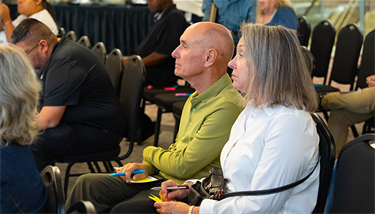 A man and a woman sitting in the audience listening to presentation
