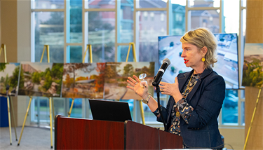 A woman presenting to an audience from a podium