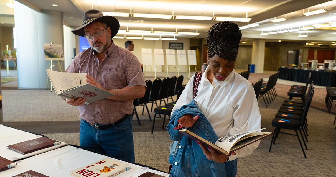 A man in a cowboy hat and a woman looking at yearbooks