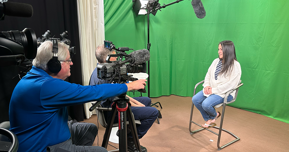 A woman being interviewed in a studio with a green screen